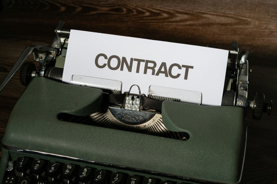 The word CONTRACT typed on paper in a vintage typewriter