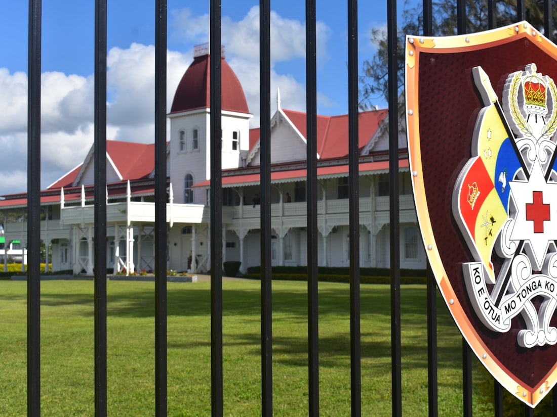 The Royal Palace in Nuku'alofa, Tonga, viewed through its fence with the Tongan coat of arms